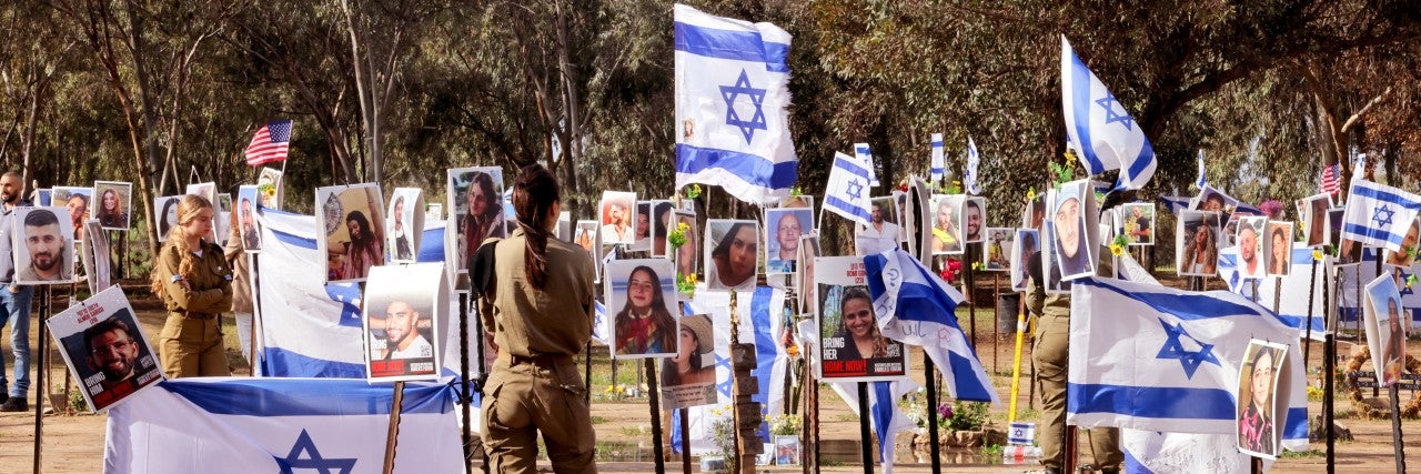 TOPSHOT - Israeli soldiers walk among portraits of people taken captive or killed by Hamas militants during the Supernova music festival on October 7, during a visit at the site where the deadly incident took place near Kibbutz Reim in southern Israel, on January 11, 2024, amid continuing battles between Israel and Hamas in Gaza. 