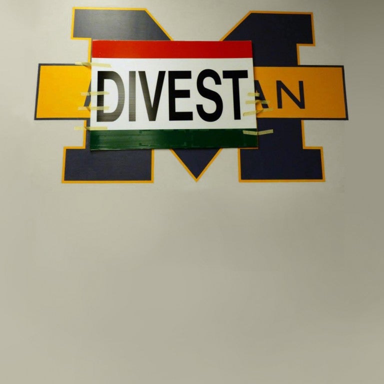 Photo with the Michigan "M" logo with the words Divest plastered over the logo